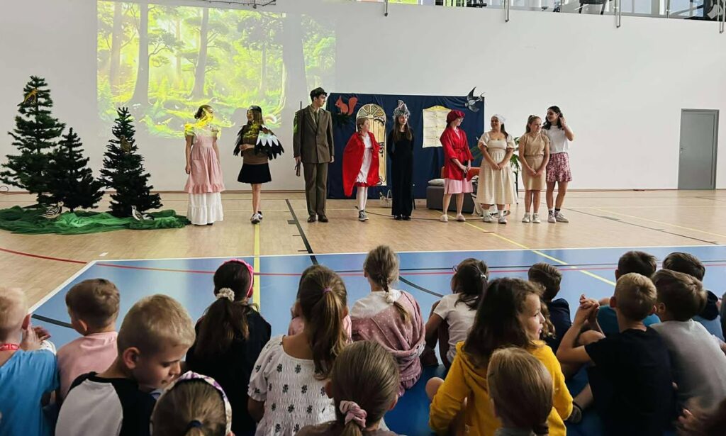 Zdjęcie przedstawia aktorów podczas przestawienia oraz widownię.